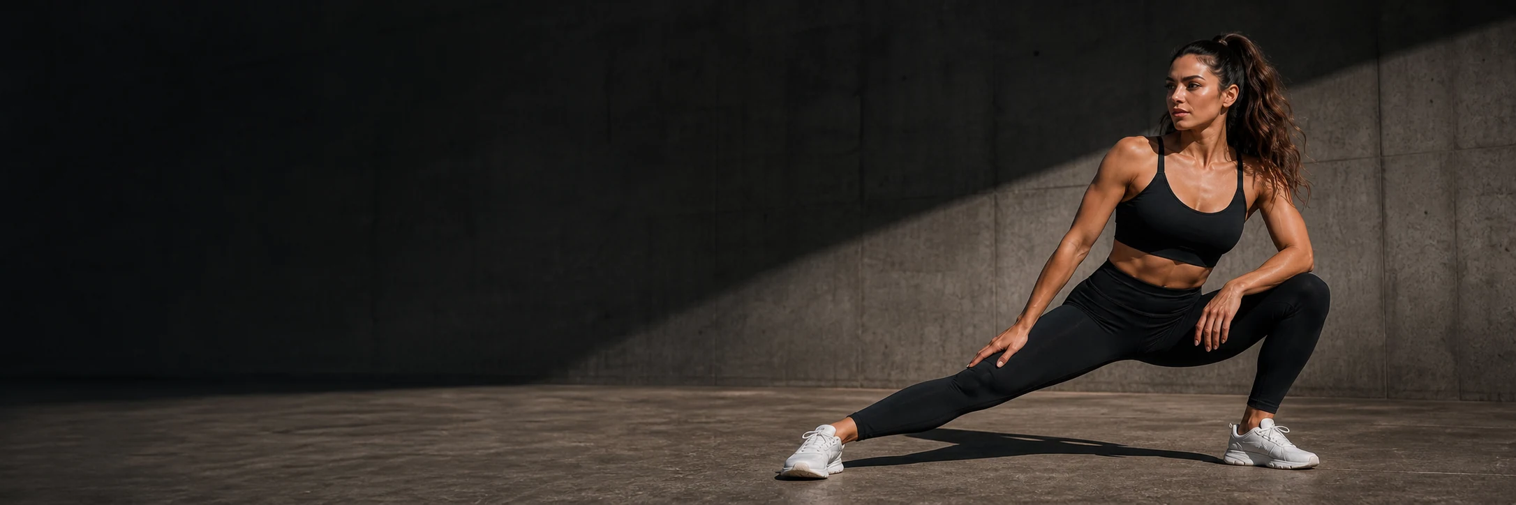 Mujer entrenando con ropa deportiva negra en un espacio de concreto